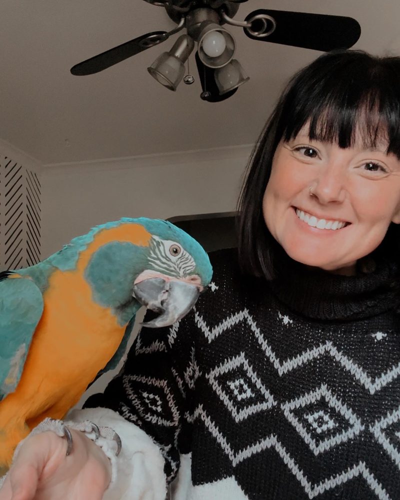 Brittany smiling with a blue-throated macaw perched on her hand